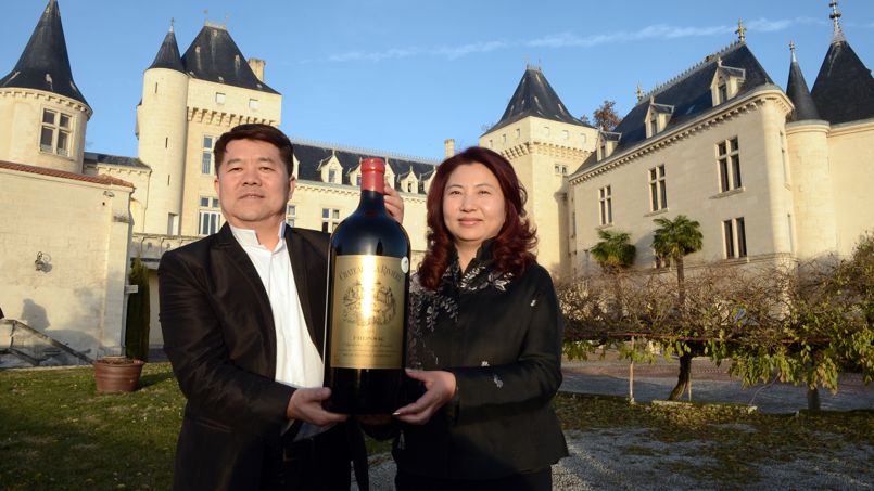 Chinese billionaire Lam Kok (L) and his spouse pose for a photograph on December 20, 2013, in front of the Chateau de La Riviere, in La Riviere. The deal which was concluded on December 19 for Chinese billionaire Lam Kok to buy a Bordeaux vineyard, le Château de La Rivière, turned to tragedy today after the helicopter which the billionaire and the vineyard's French former owner James Gregoire were using to fly over the property crashed into the Dordogne river. This photograph was taken less than an hour before the crash. The French former owner of the vineyard James Gregoire, the new Chinese buyer Lam Kok, and Lam Kok's 12-year-old son are still missing. AFP PHOTO / MEHDI FEDOUACH