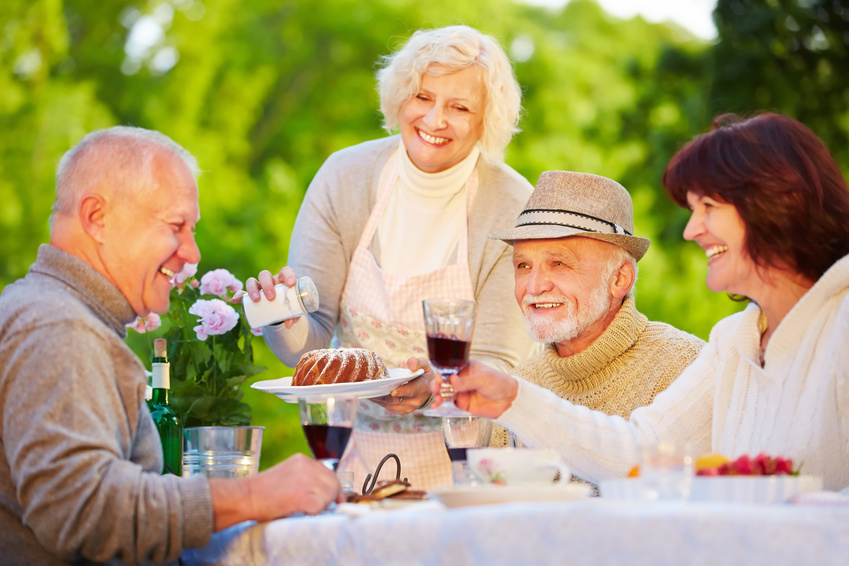 Lächelnde Gruppe Senioren feiert Geburtstag im Garten im Sommer