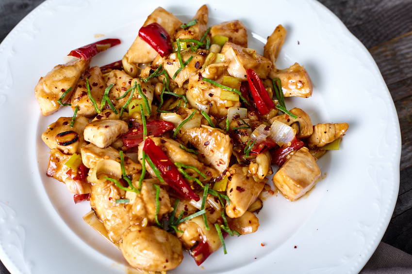 Kung Pao Chicken with Peppers, peanuts and Veggies and sticky glance sauce on wood background